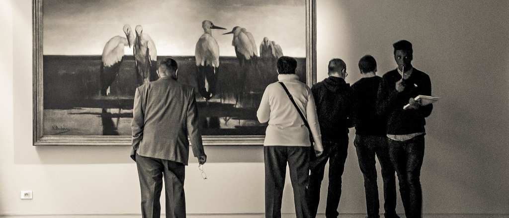 Black and white image of museum-goers in front of painting
